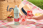 Penrhos Strawberry Gin bottle with a glass of strawberry gin on a picnic blanket.