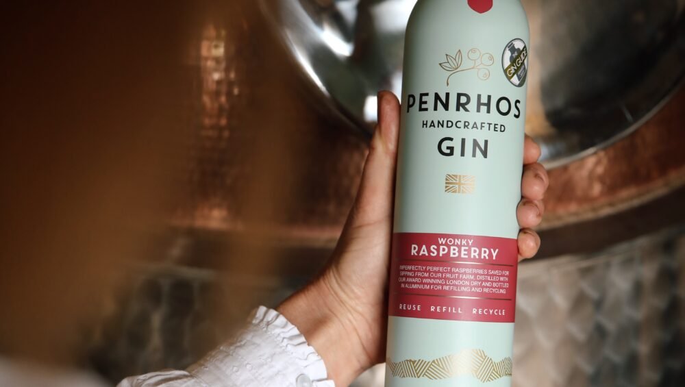 Penrhos Wonky Raspberry Gin in front of coppa still at Penrhos Distillery